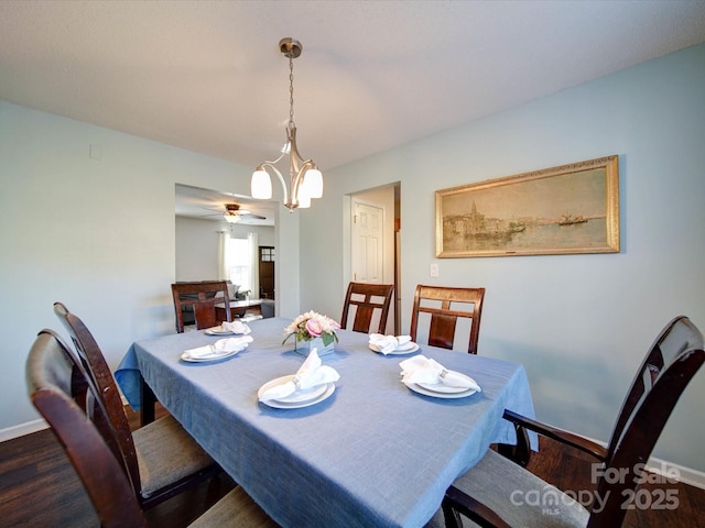 dining area featuring baseboards, a notable chandelier, and wood finished floors