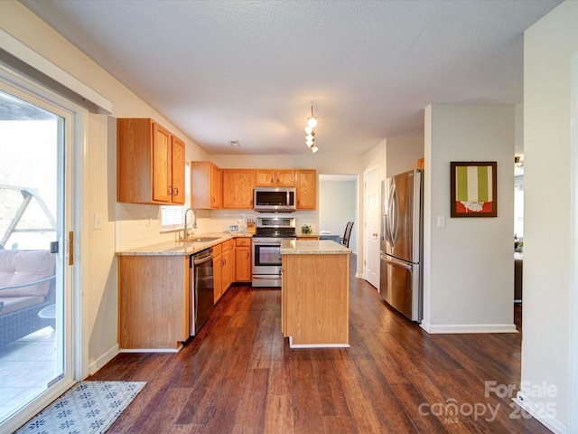 kitchen with dark wood-type flooring, a sink, a center island, stainless steel appliances, and light stone countertops