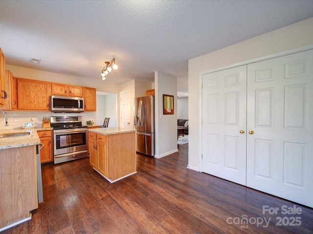 kitchen featuring visible vents, light stone counters, a kitchen island, stainless steel appliances, and dark wood-style flooring