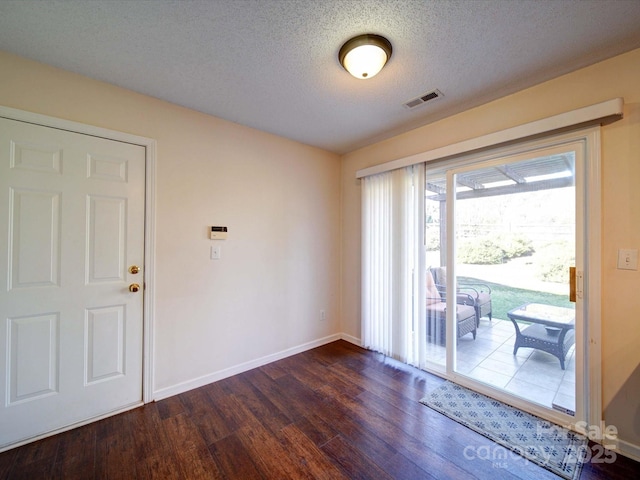 empty room featuring visible vents, baseboards, a textured ceiling, and dark wood-style flooring