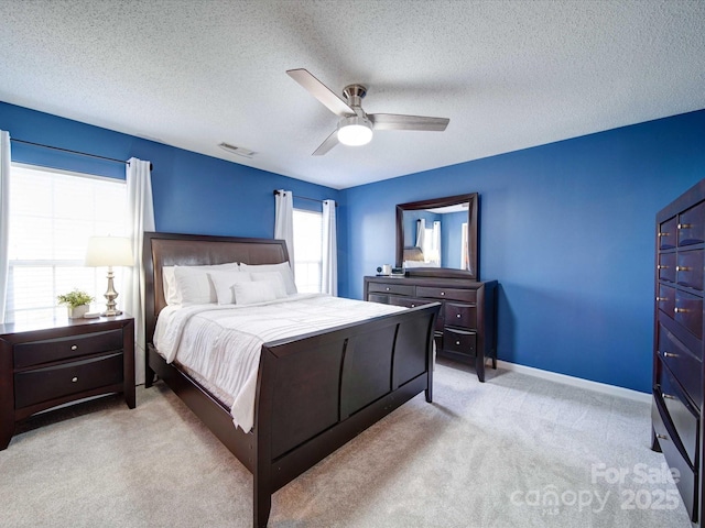 bedroom featuring baseboards, visible vents, ceiling fan, a textured ceiling, and light carpet