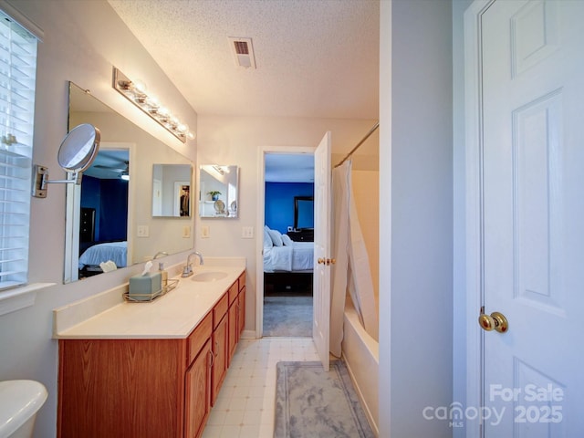 ensuite bathroom with visible vents, vanity, ensuite bathroom, tile patterned floors, and a textured ceiling