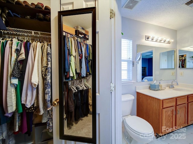 bathroom with visible vents, toilet, a textured ceiling, and vanity