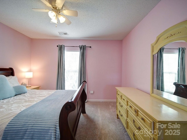 carpeted bedroom featuring ceiling fan, baseboards, visible vents, and a textured ceiling