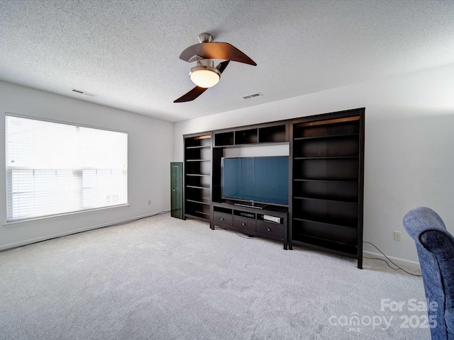 unfurnished living room featuring visible vents, carpet, ceiling fan, and a textured ceiling