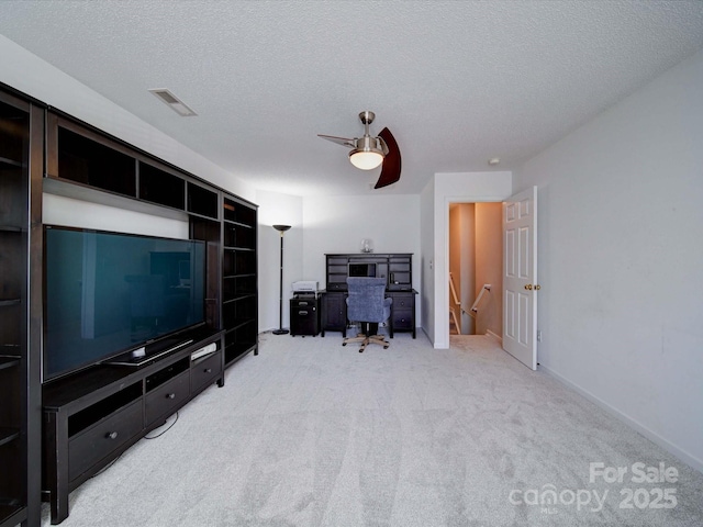 office area featuring light carpet, a ceiling fan, visible vents, and a textured ceiling