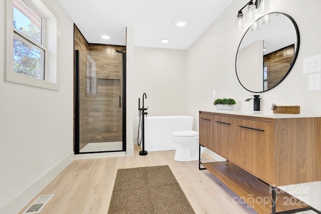 bathroom with visible vents, a shower stall, wood finished floors, a soaking tub, and vanity