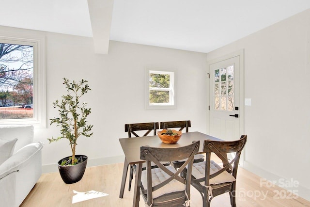 dining area featuring plenty of natural light, baseboards, and light wood finished floors