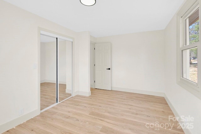 unfurnished bedroom with a closet, light wood-style flooring, and baseboards