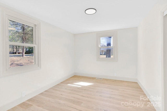 spare room with visible vents, baseboards, and wood finished floors