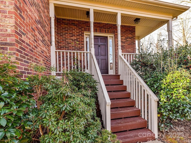 property entrance featuring a porch and brick siding