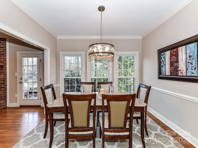 dining area featuring a notable chandelier, a healthy amount of sunlight, wood finished floors, and ornamental molding