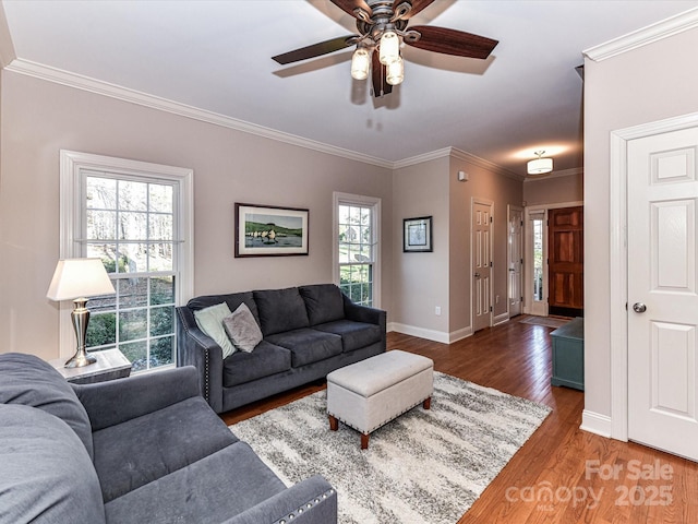 living room with a ceiling fan, crown molding, baseboards, and wood finished floors