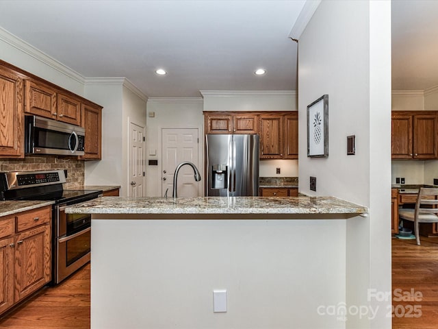 kitchen with tasteful backsplash, appliances with stainless steel finishes, wood finished floors, and brown cabinetry