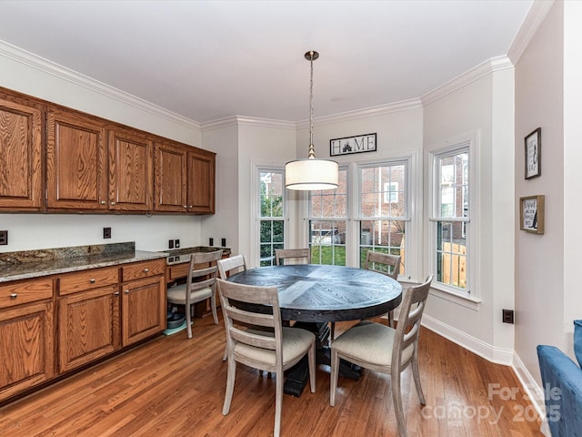 dining room with light wood-type flooring, baseboards, and ornamental molding