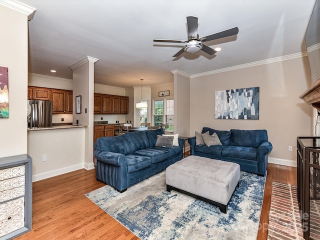 living area featuring light wood-style flooring, a ceiling fan, ornamental molding, recessed lighting, and baseboards