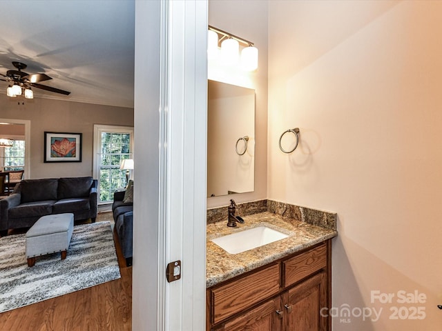 bathroom featuring ceiling fan, wood finished floors, vanity, and ornamental molding