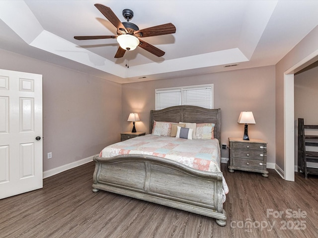 bedroom featuring a raised ceiling, wood finished floors, and baseboards