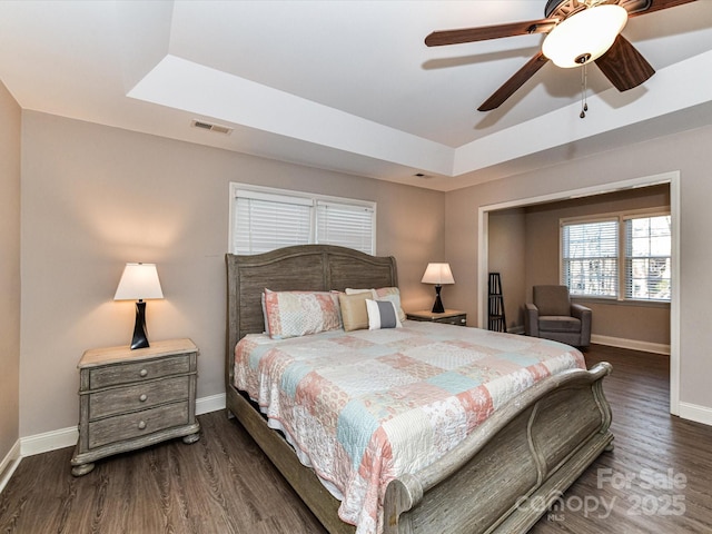 bedroom with visible vents, a raised ceiling, and wood finished floors