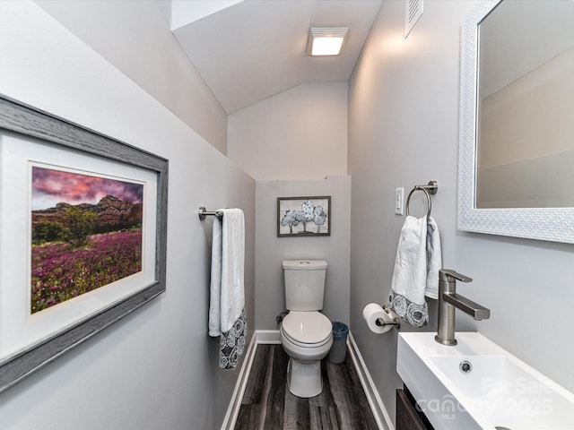 half bath with visible vents, baseboards, toilet, lofted ceiling, and wood finished floors