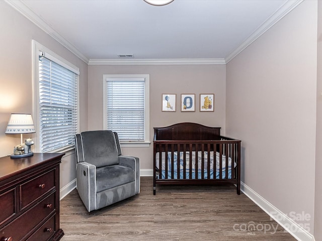 bedroom with crown molding, wood finished floors, visible vents, and baseboards