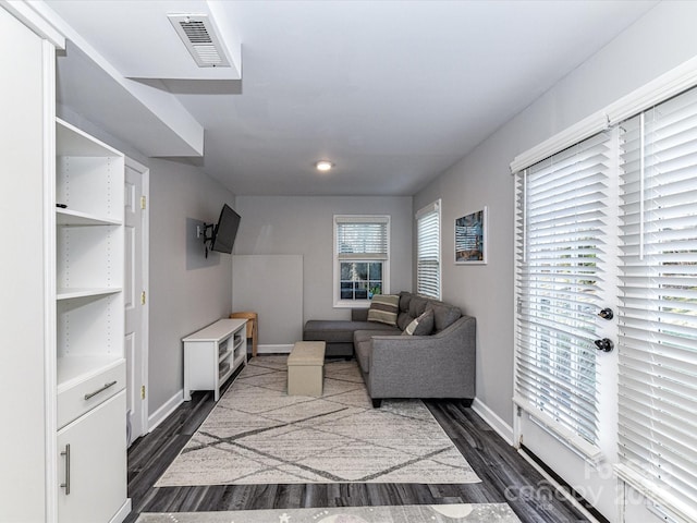 living area with visible vents, baseboards, and dark wood finished floors