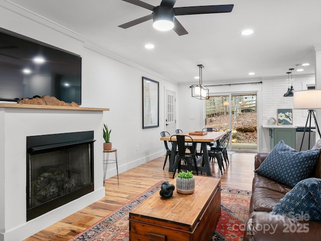 living area featuring recessed lighting, a fireplace, wood finished floors, and crown molding