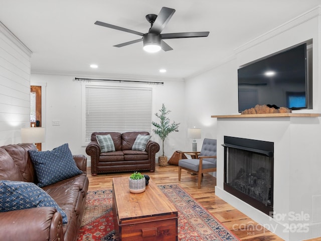 living room with wood finished floors, recessed lighting, a fireplace, crown molding, and ceiling fan