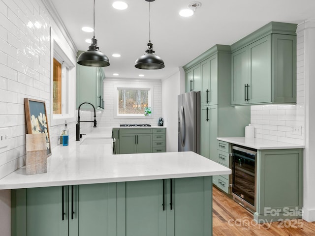 kitchen featuring green cabinetry, wine cooler, stainless steel refrigerator with ice dispenser, and a sink