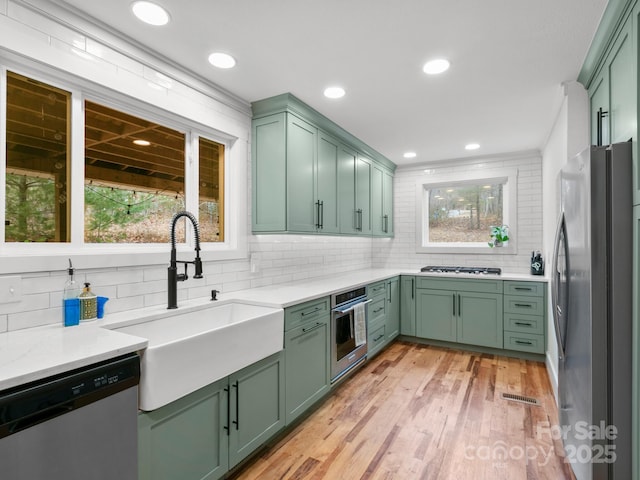 kitchen with a healthy amount of sunlight, stainless steel appliances, green cabinets, and a sink