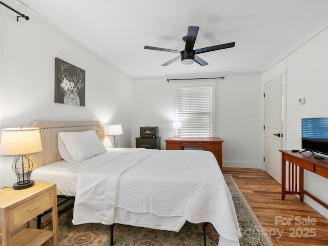 bedroom with a ceiling fan, crown molding, wood finished floors, and baseboards