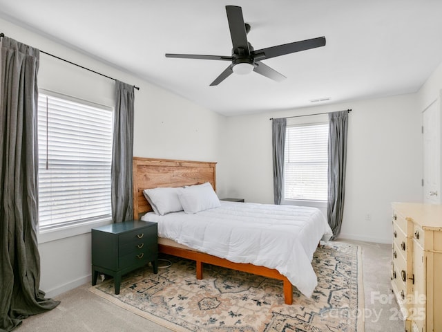 bedroom with visible vents, baseboards, light carpet, and a ceiling fan