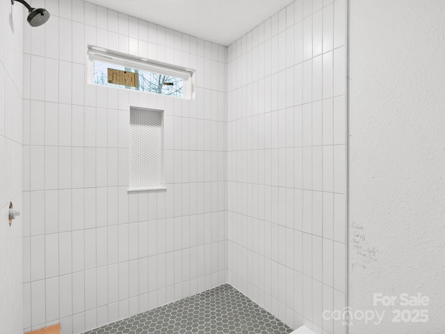 full bathroom featuring tiled shower and a textured wall