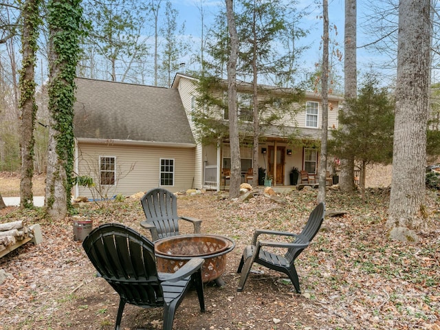 back of house with roof with shingles and an outdoor fire pit