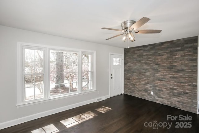 foyer with brick wall, baseboards, dark wood-type flooring, and ceiling fan