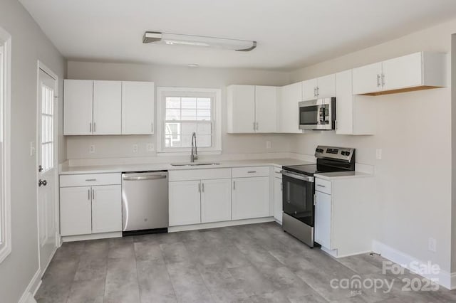 kitchen with a sink, stainless steel appliances, white cabinets, and light countertops