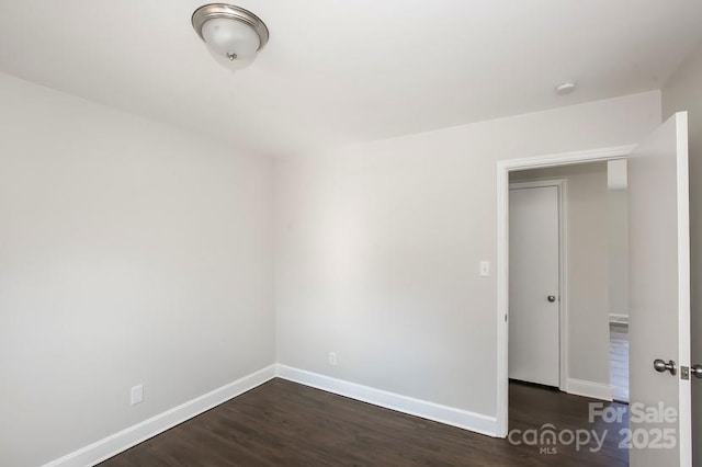 empty room with baseboards and dark wood-style floors