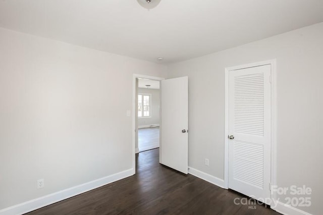 unfurnished bedroom with baseboards and dark wood finished floors