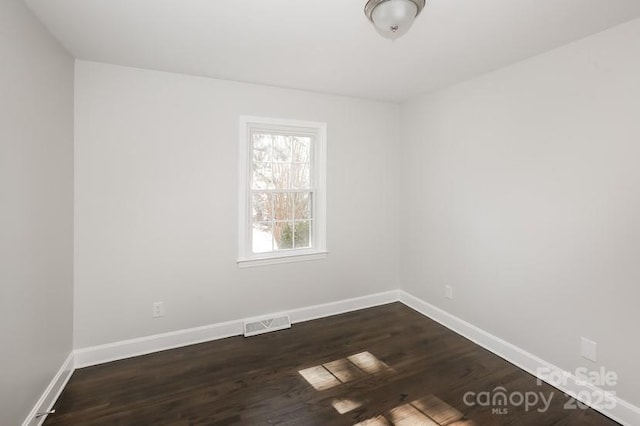 unfurnished room featuring visible vents, baseboards, and dark wood-style floors