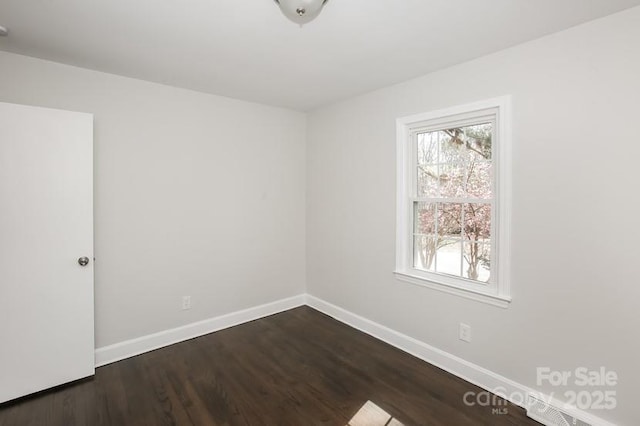 spare room featuring dark wood finished floors and baseboards