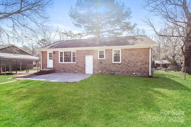 rear view of property with brick siding, a shingled roof, fence, a lawn, and a patio area