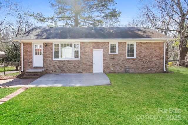 rear view of house featuring a yard, brick siding, roof with shingles, and fence