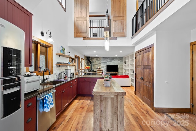 kitchen featuring oven, butcher block countertops, light wood-style flooring, a sink, and dishwasher