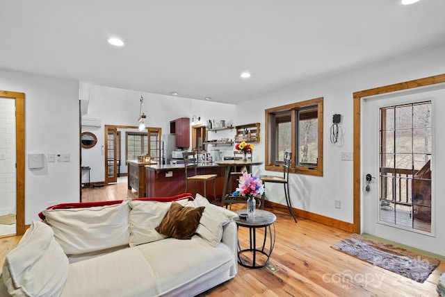 living area featuring recessed lighting, light wood-style flooring, and a wall mounted AC