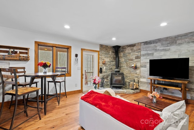 living area featuring a wood stove, recessed lighting, wood finished floors, and baseboards