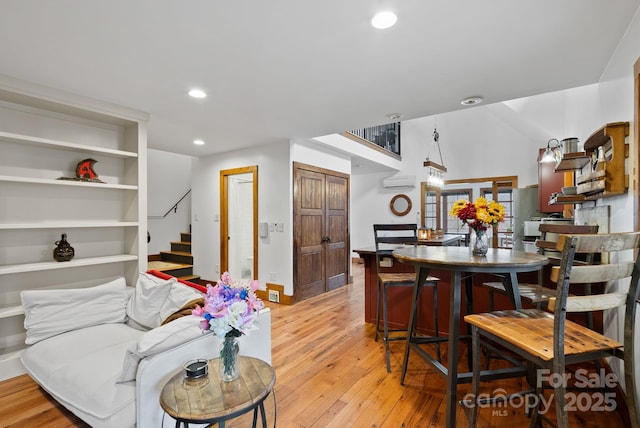 living area with baseboards, light wood-style flooring, recessed lighting, stairs, and an AC wall unit