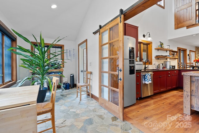 interior space featuring stone finish flooring, a barn door, recessed lighting, high vaulted ceiling, and a sink