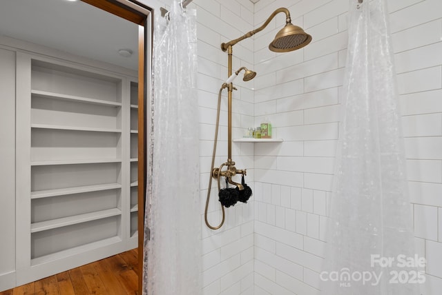 bathroom featuring tiled shower and wood finished floors