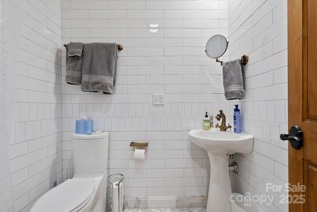 half bathroom featuring toilet and tile walls