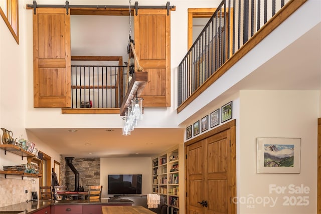 living area featuring a barn door, a wood stove, and a high ceiling